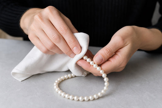 Hands gently cleaning a pearl necklace with a soft cloth