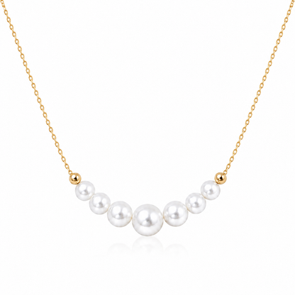 Gold-tone S925 sterling silver necklace with seven graduated round white freshwater pearls on a white background
