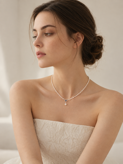 Model wearing the freshwater pearl butterfly necklace with a silver butterfly and blue zircon, viewed from the side