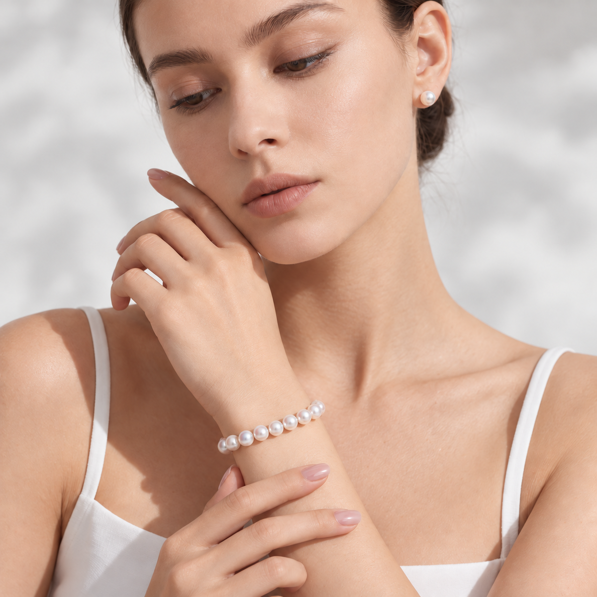 Model wearing the PERLAVELLE PL3 round freshwater pearl bracelet with the clasp turned inward, in warm natural light