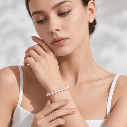 Model wearing the PERLAVELLE PL3 round freshwater pearl bracelet with the clasp turned inward, in warm natural light