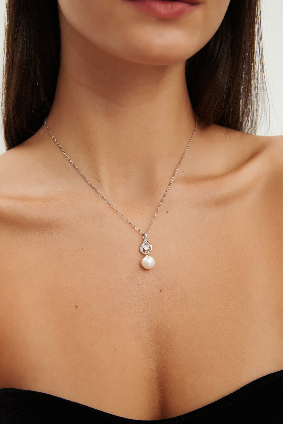 Starlit Drop freshwater pearl pendant necklace resting at the neckline, showing the intertwined sterling silver setting and cubic zirconia accents.