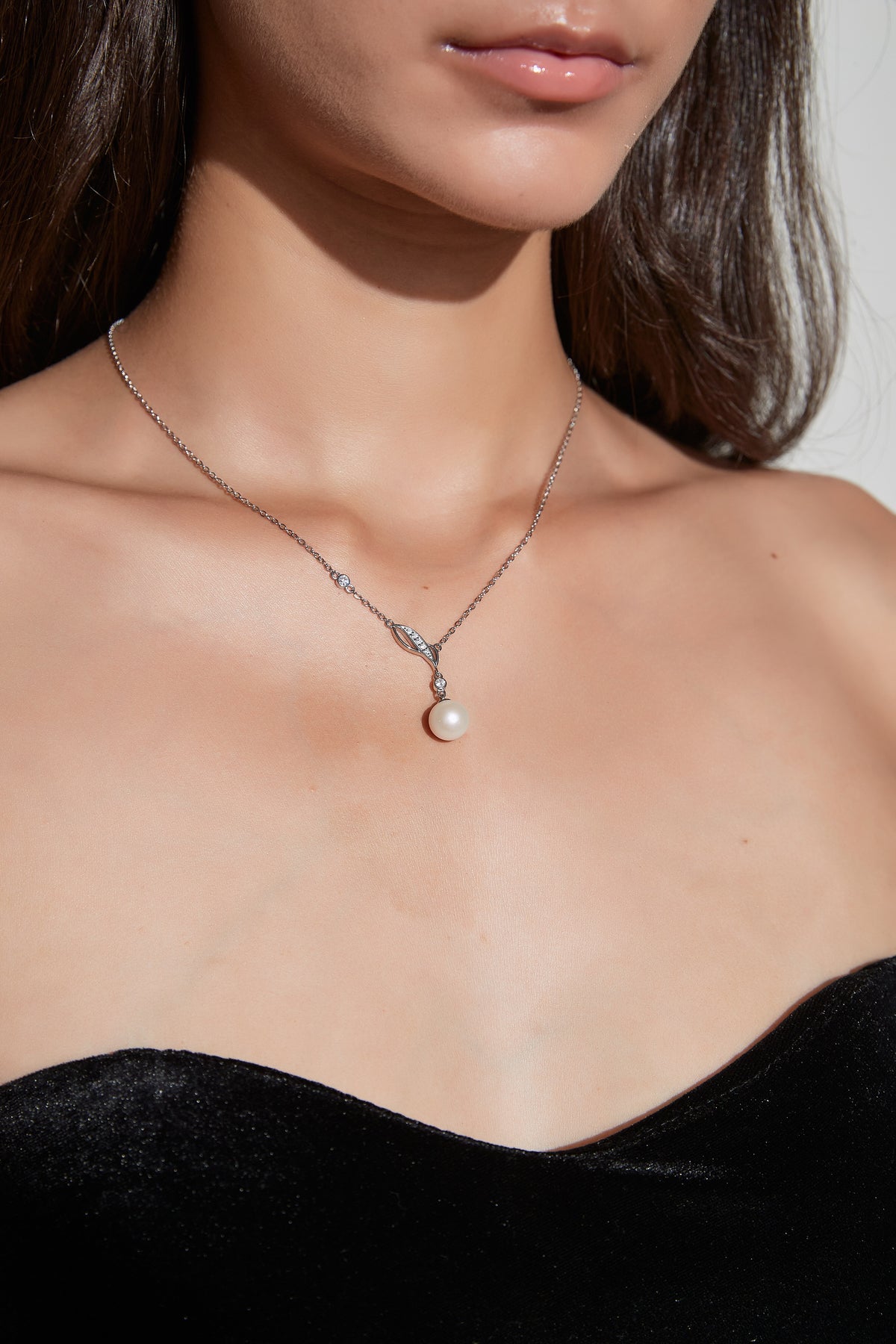 Willow Dew freshwater pearl pendant necklace worn at the neckline, with a leaf-shaped sterling silver detail and cubic zirconia accents.